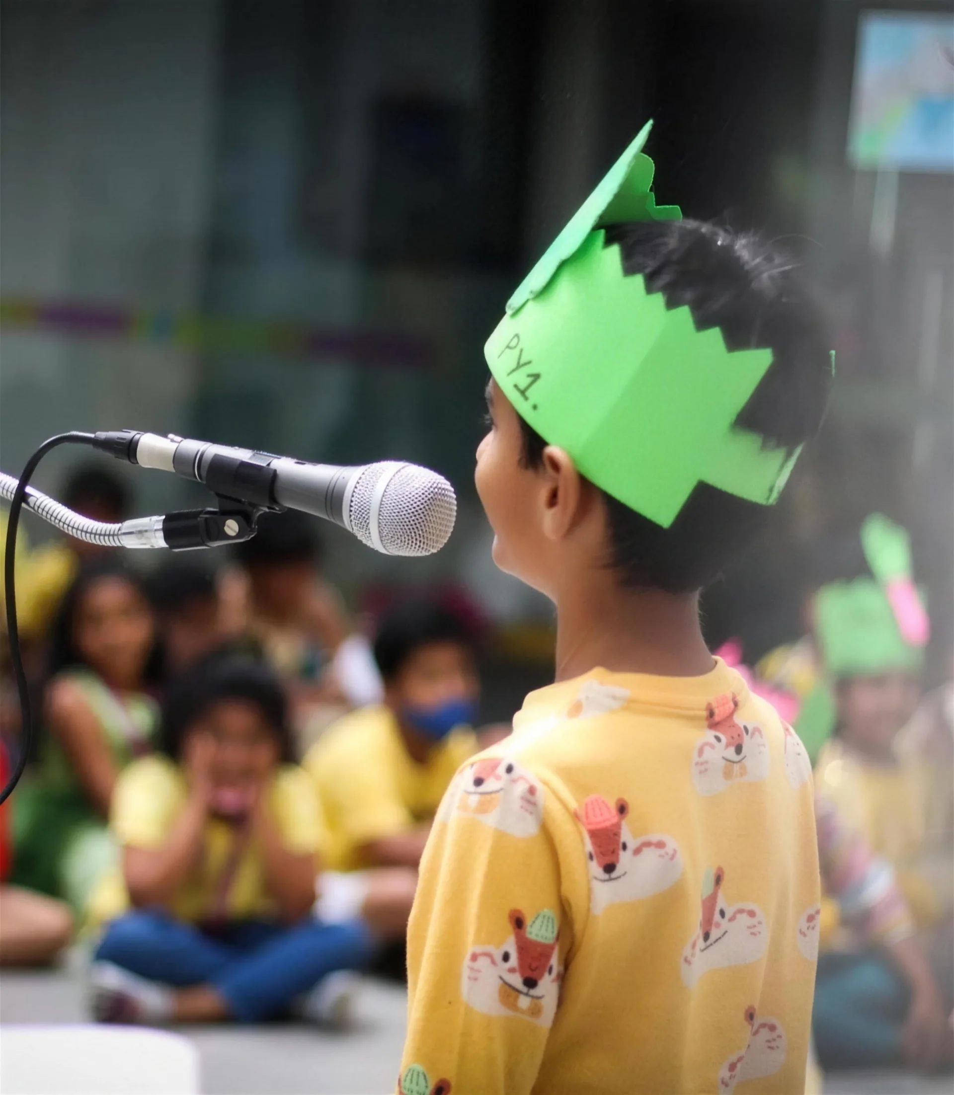 A young student speaking into a microphone on stage