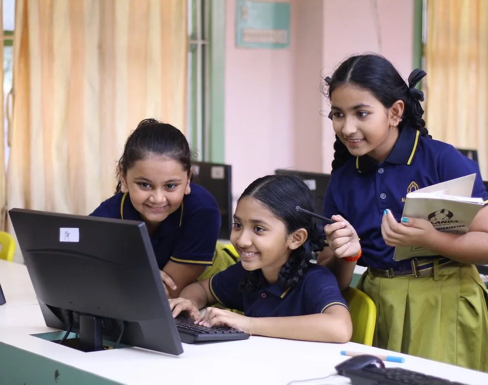 Three Nalanda Vidya Niketan students working together at a computer