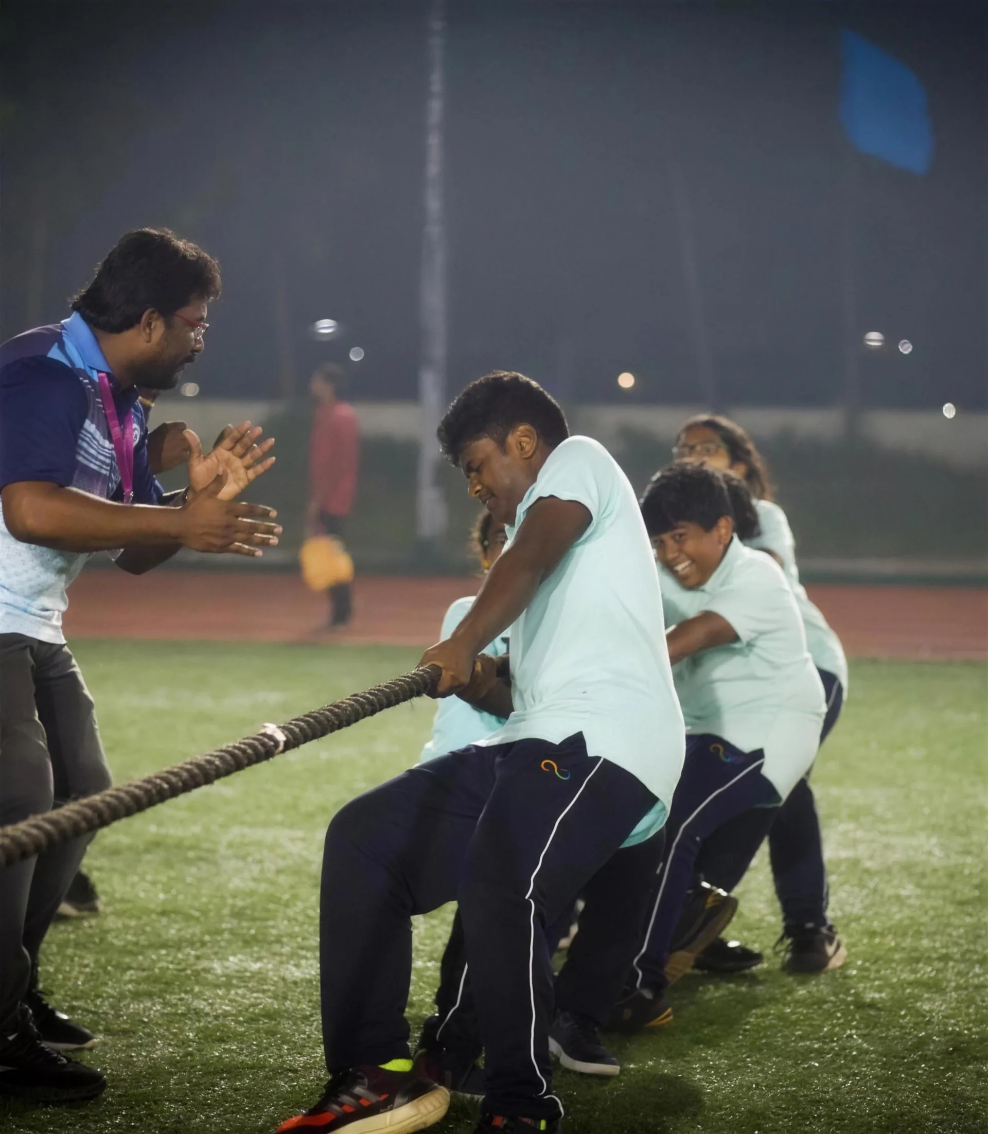 Students in a tug-of-war under floodlights